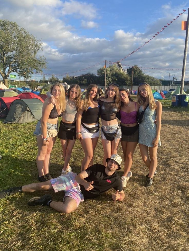 a group of young women standing next to each other on top of a grass covered field