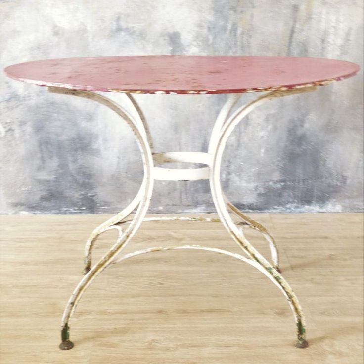 a small table with a red top on a wooden floor in front of a wall