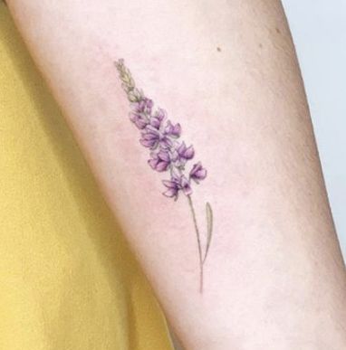 a small purple flower tattoo on the arm