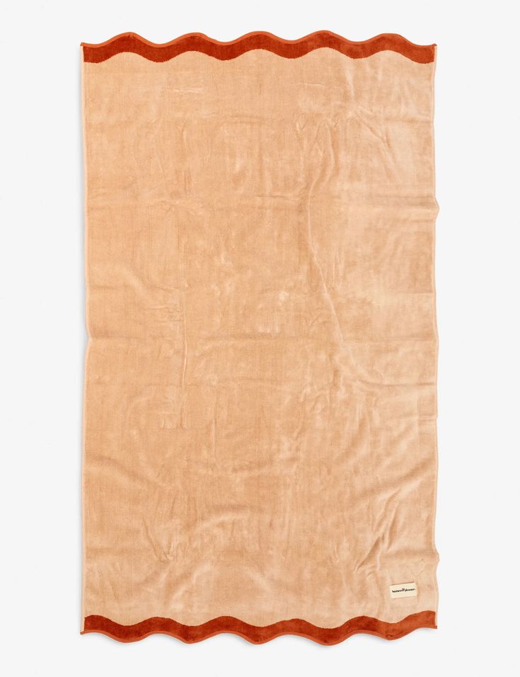 an orange and brown blanket with scalloped edges on a white background in the shape of a rectangle