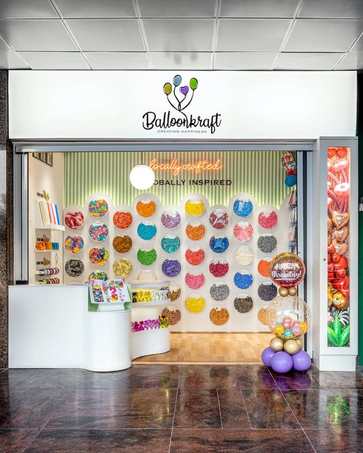 a store front with an assortment of doughnuts on the wall and balloons hanging from the ceiling