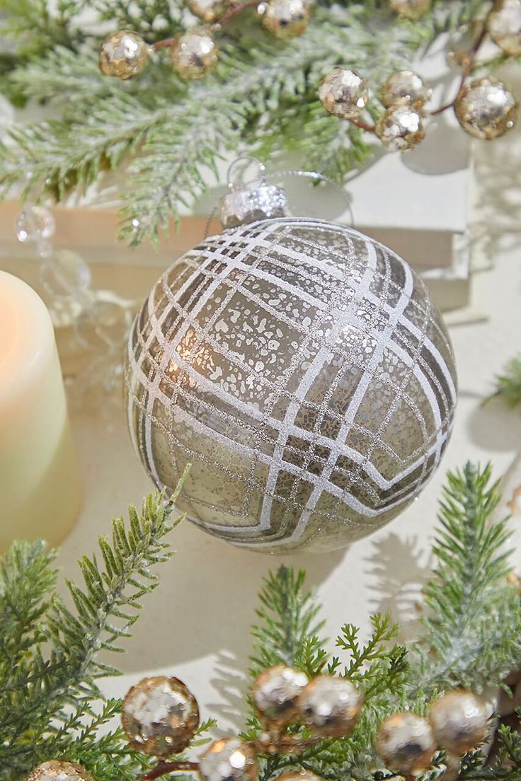 a silver ornament sitting on top of a christmas tree next to a candle