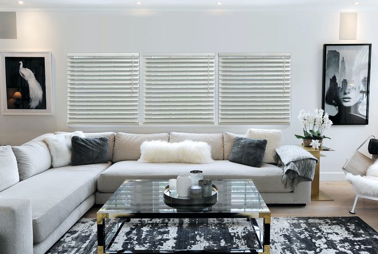 a living room filled with white furniture and pillows on top of a rug next to a coffee table