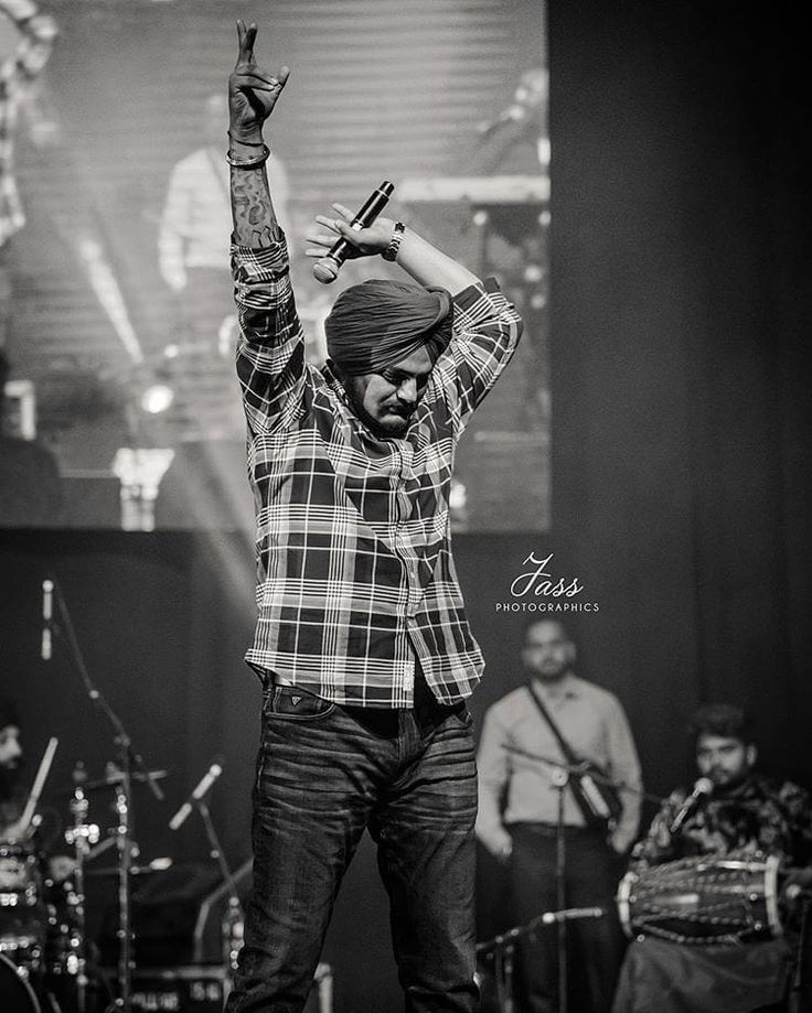 a man standing on top of a stage holding his hands up in the air with other people behind him