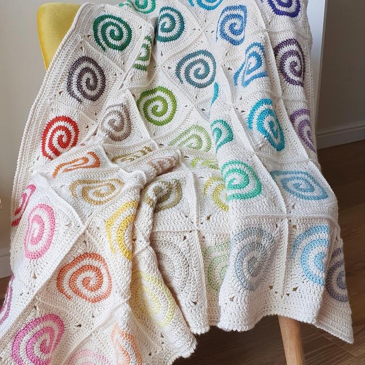 a white crocheted blanket sitting on top of a chair next to a yellow chair