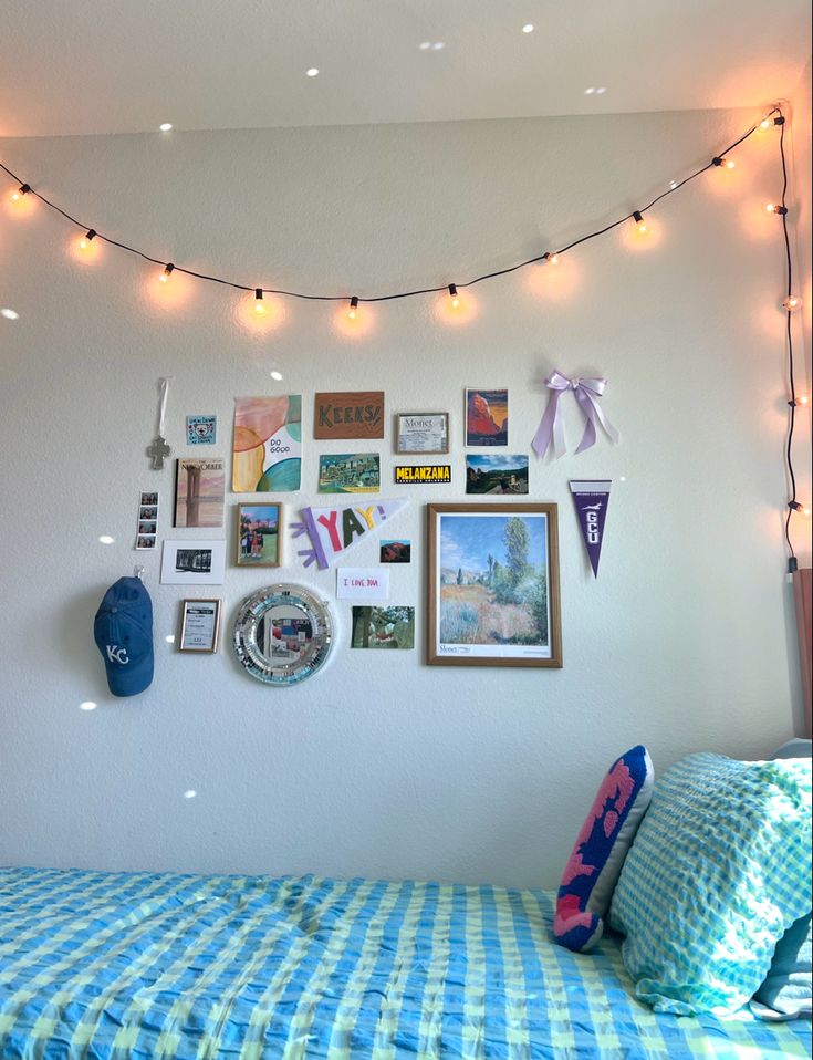 a bedroom with lights strung from the ceiling and pictures on the wall above the bed