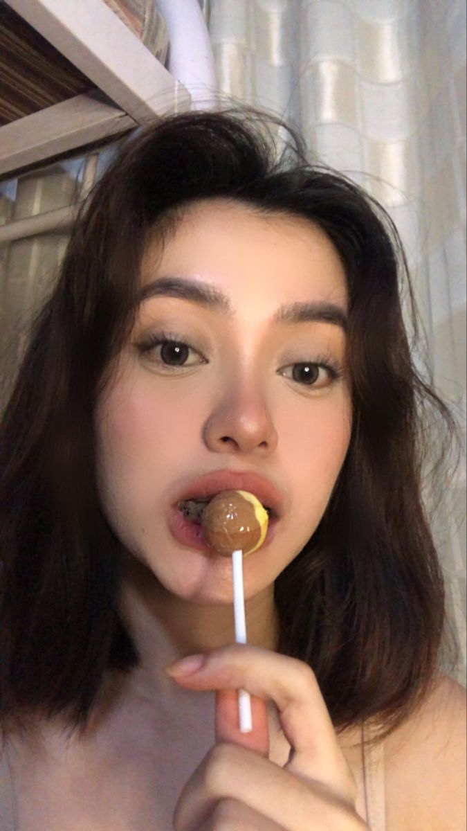 a woman holding a lollipop in her mouth