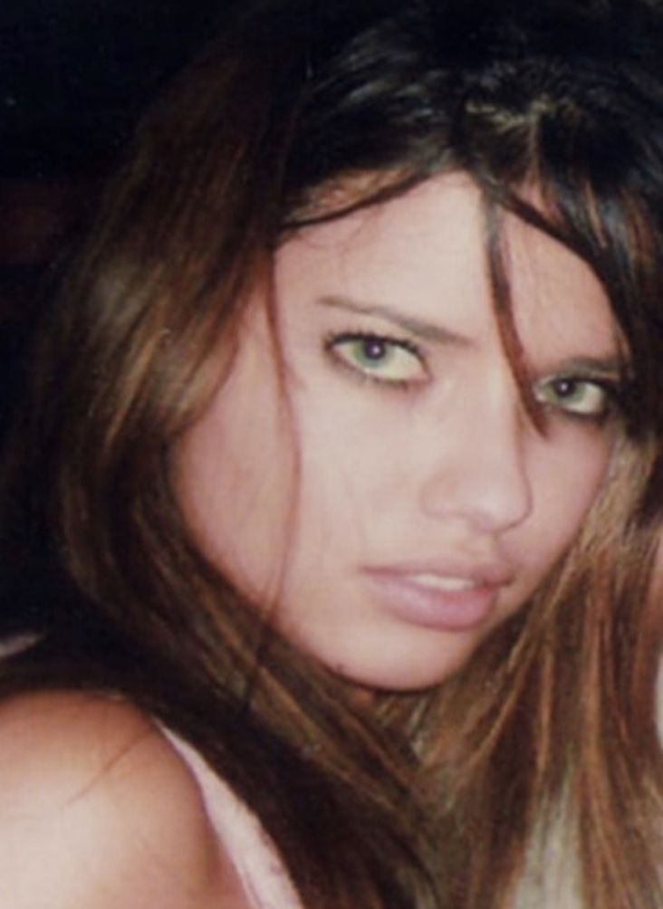 a woman with long hair and green eyes posing for the camera while holding a cell phone up to her ear