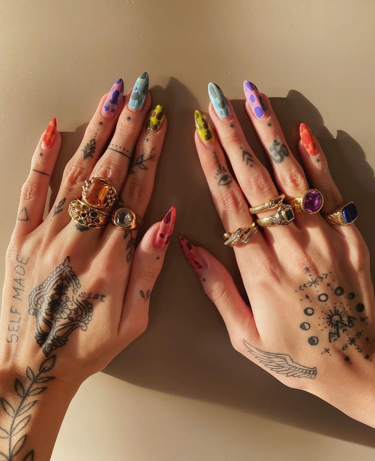 two women's hands with tattoos and rings on them