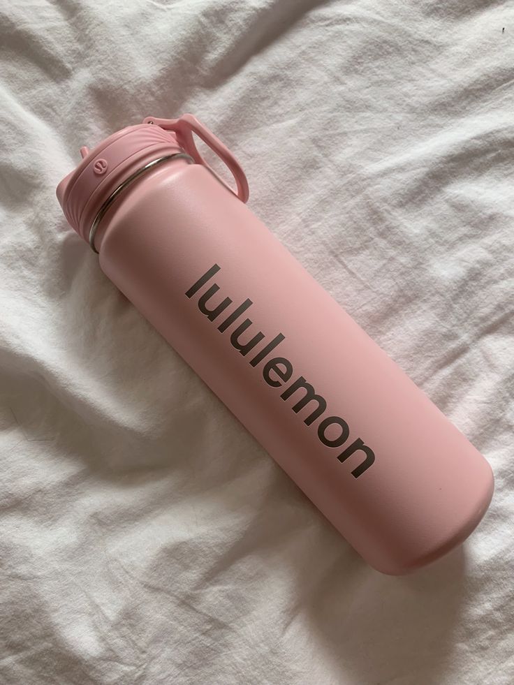 a pink water bottle sitting on top of a bed