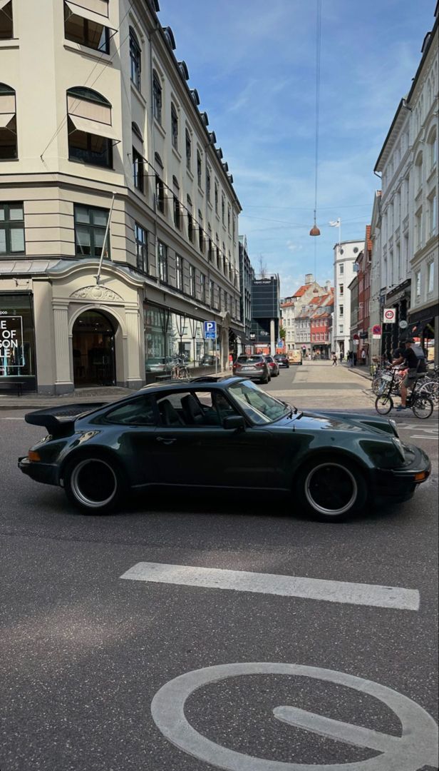 a black sports car driving down a street next to tall buildings