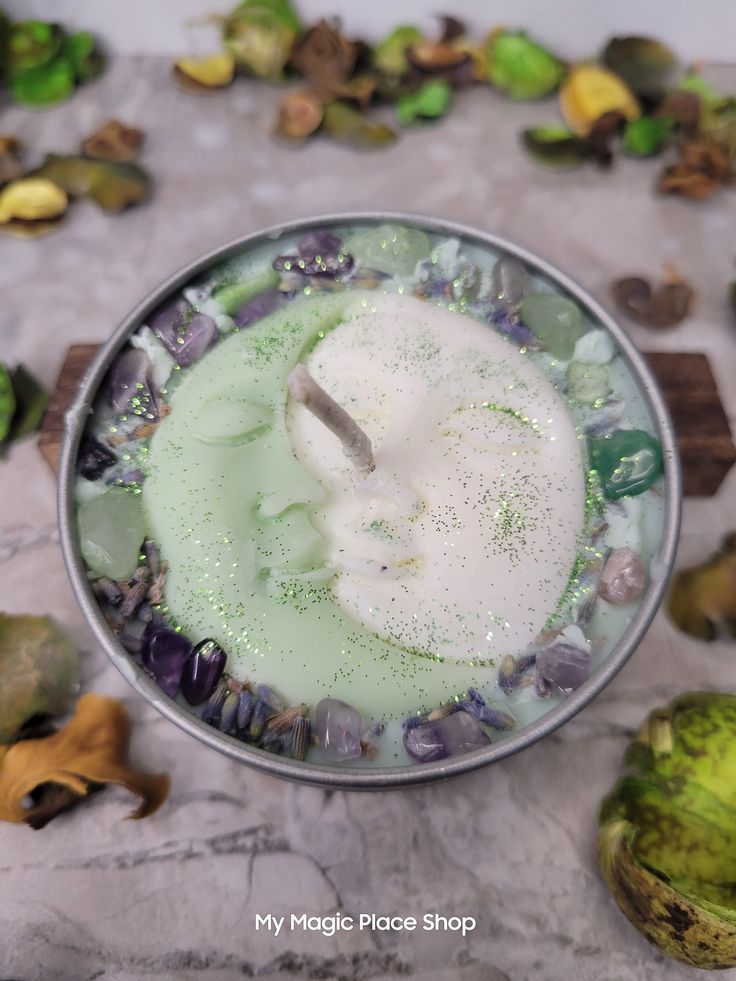 a cup filled with green liquid surrounded by leaves and other things on the table top