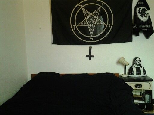 a bed with a black blanket on top of it next to two wall hangings