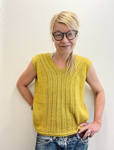 a woman wearing glasses standing in front of a wall with her hands on her hips