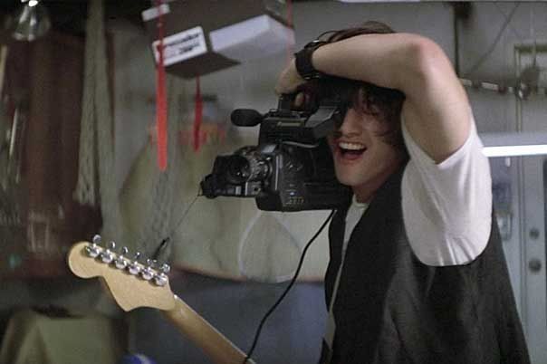 a man holding a guitar and recording something