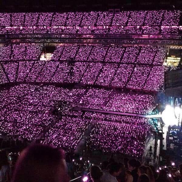 a large group of people standing in front of a stage with lots of purple lights