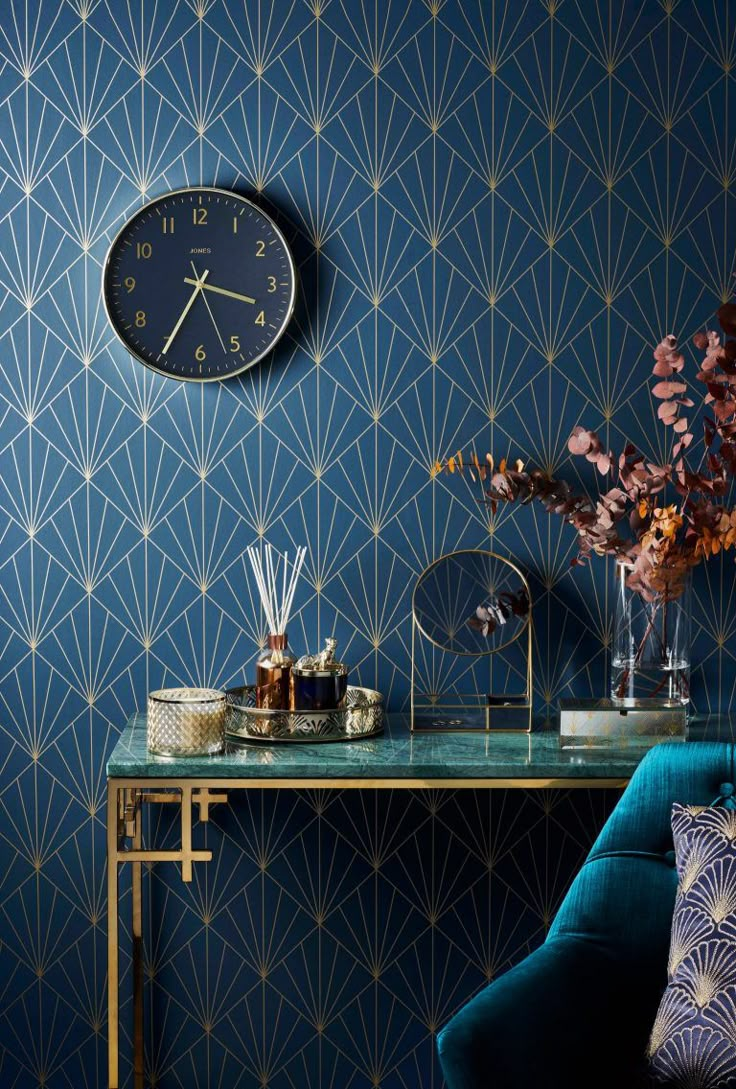 a blue room with a clock on the wall next to a green chair and table