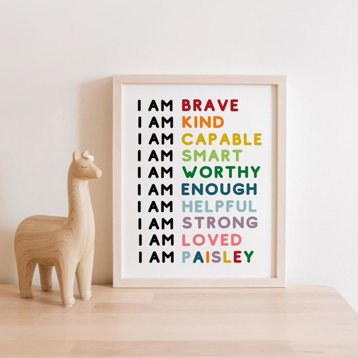 a wooden toy llama next to a framed art print with the words i am brave on it