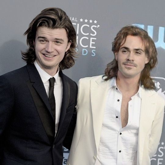 two men standing next to each other on a red carpet