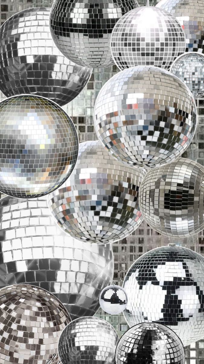 many shiny disco balls hanging from the ceiling in front of a mirror wall with black and white squares