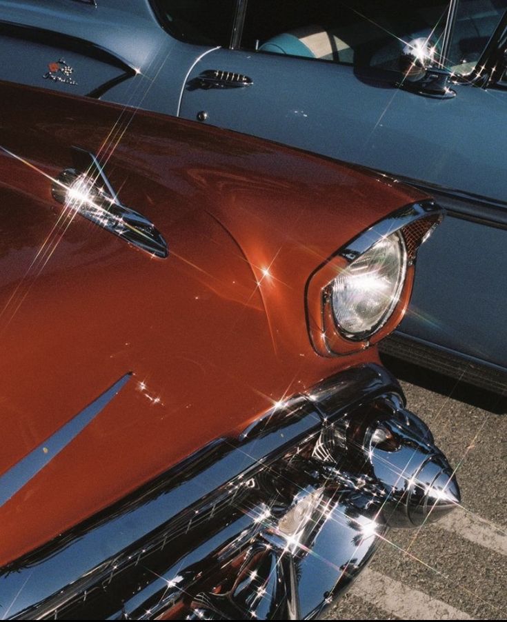 the front end of an old car parked in a parking lot