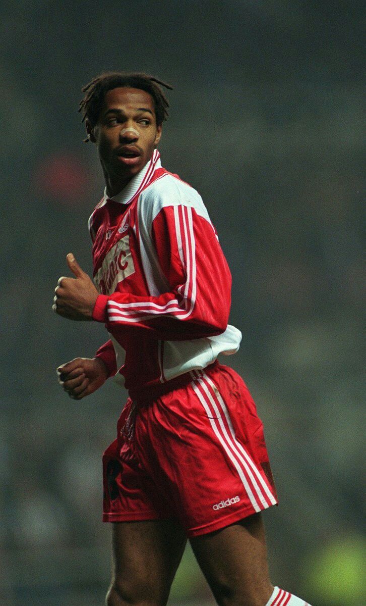 a man in red and white soccer uniform running with a soccer ball on the field