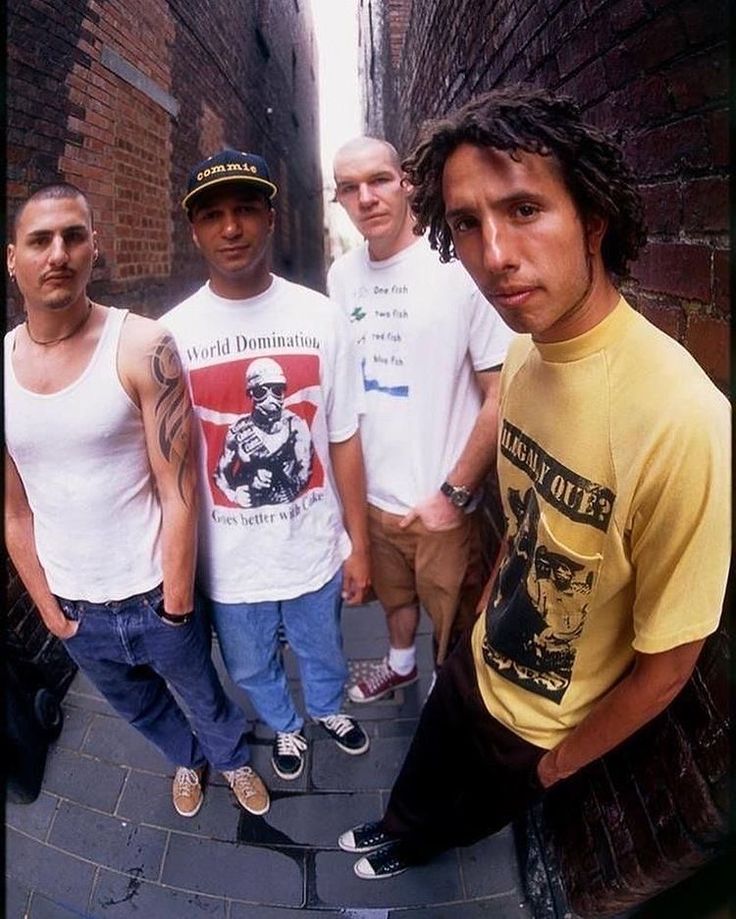 a group of young men standing next to each other on a brick walkway in an alleyway