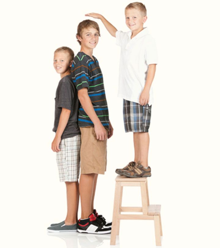 two boys standing on a stool with their arms around each other and pointing at something