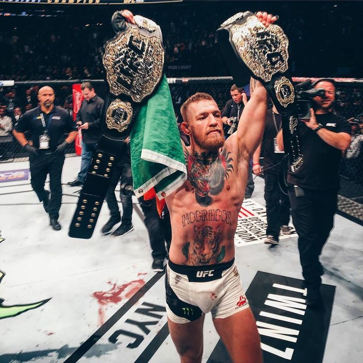 the man is holding his arms up in victory with two flags on each side of him