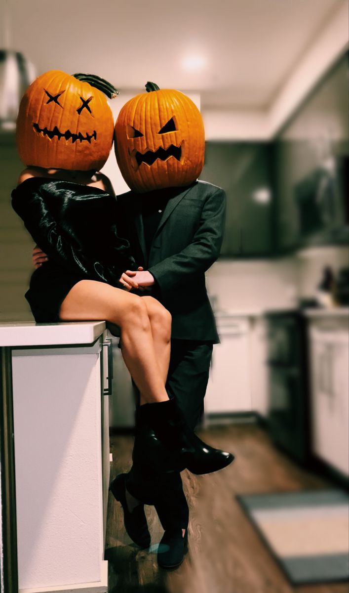 a man and woman dressed up as jack - o'- lanterns sitting on top of each other