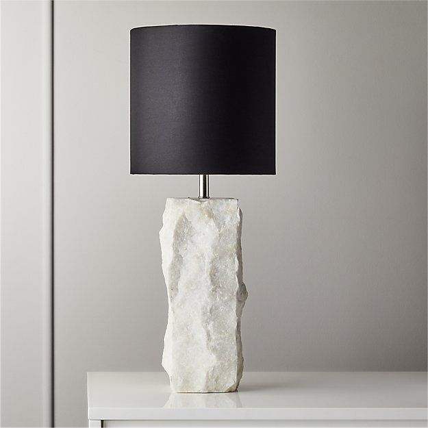 a table lamp with a black shade on it and a white rock like object next to it