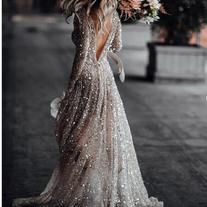 the back of a woman's dress with flowers in her hair and long sleeves