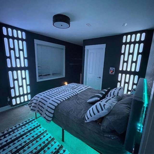 a bed room with a neatly made bed and some lights on the wall above it