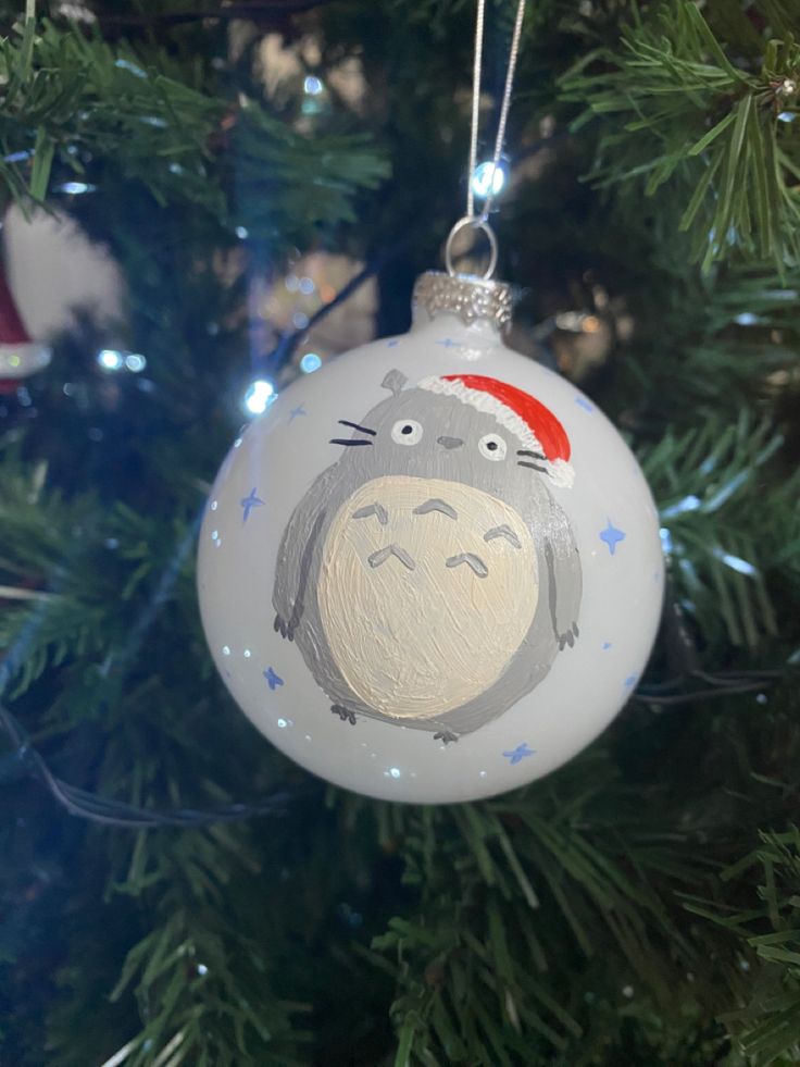 a christmas ornament hanging from the tree with a totoro face on it