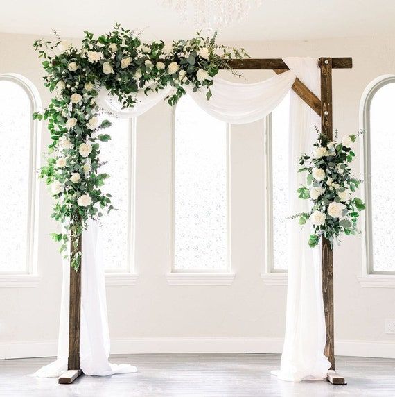 the wedding arch is decorated with white flowers and greenery