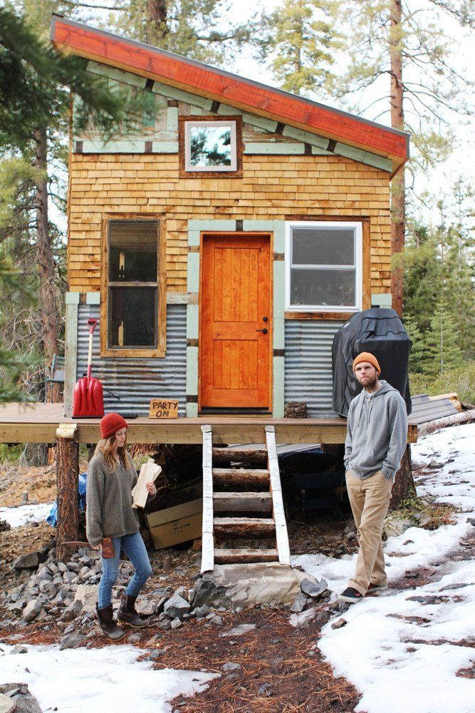 two people standing in front of a tiny house