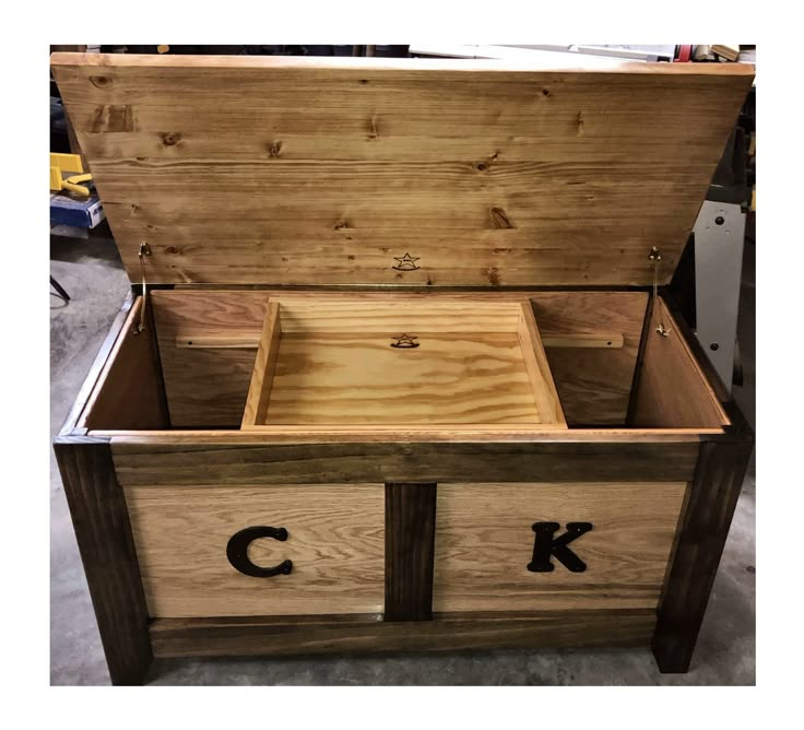 an open wooden box with the letters k and c in black on it's sides