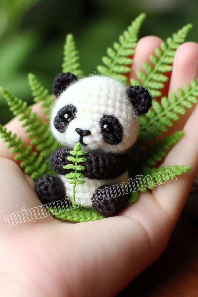 a small stuffed panda bear sitting on top of a green leafy plant in someone's hand