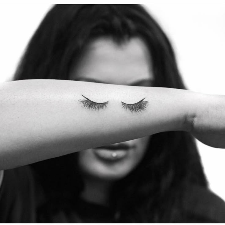 a woman is holding her arm with eyelashes on it