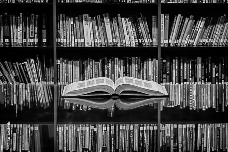 an open book sitting on top of a table in front of a bookshelf