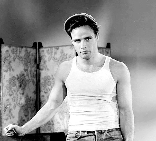 black and white photograph of a man in tank top standing with his hands on his hips