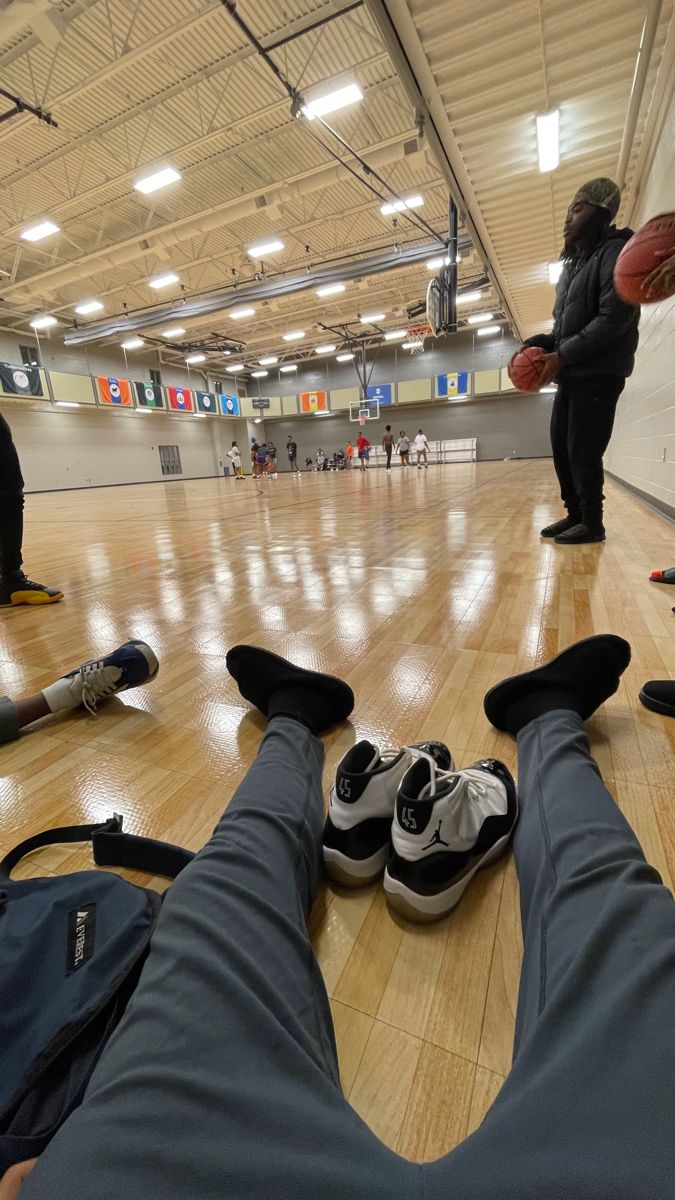 people are playing basketball in an indoor gym with their feet on the floor and one is holding a ball