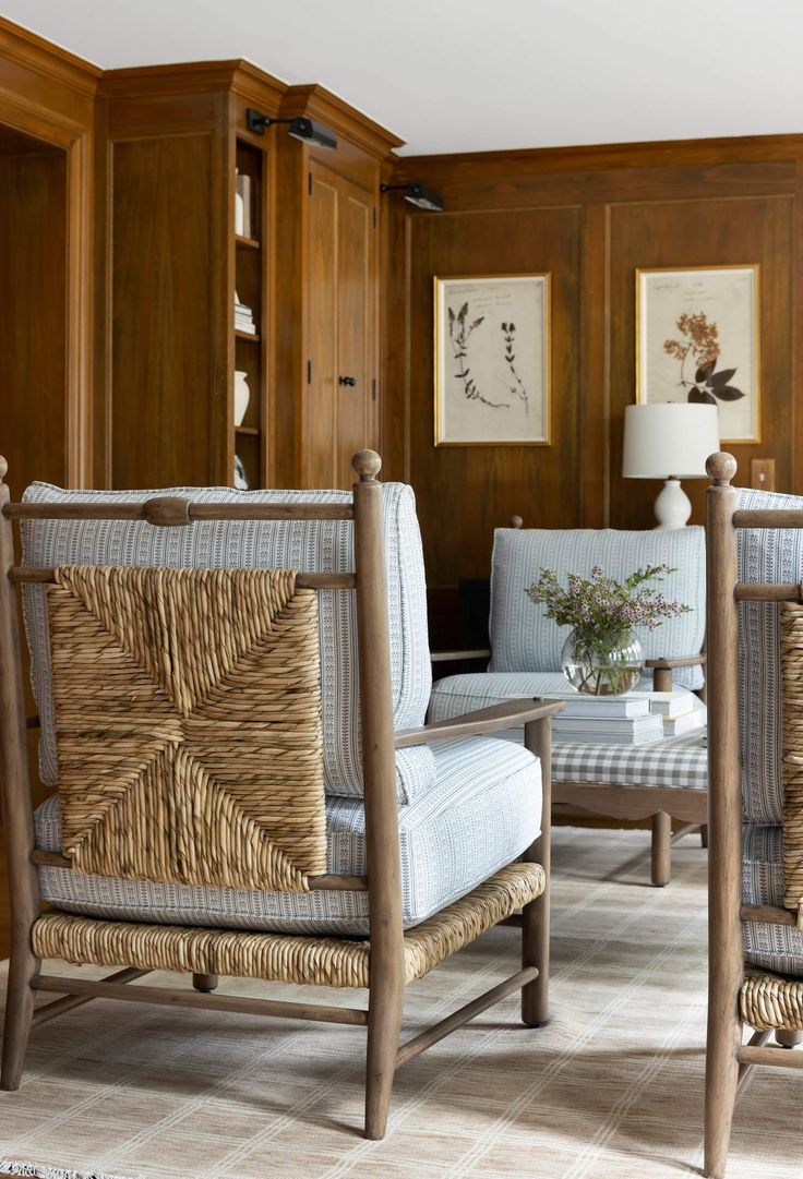 two chairs and a table in a room with wood paneling on the wall behind them