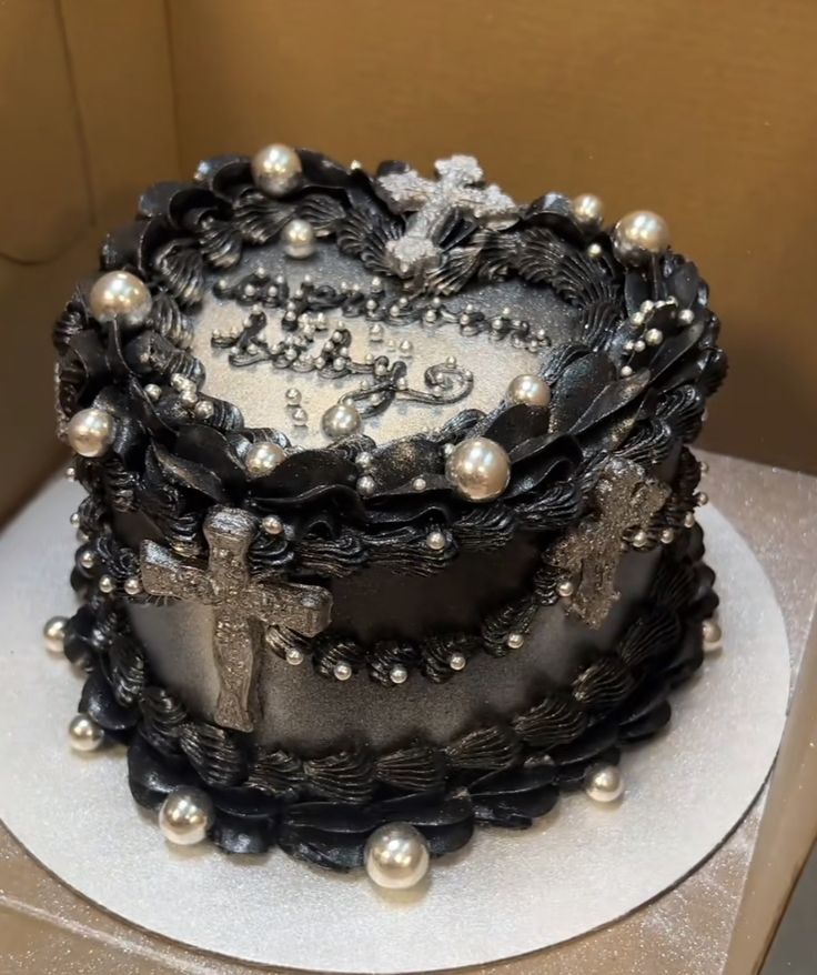 a black and white decorated cake on top of a table with silver pearls around the edges