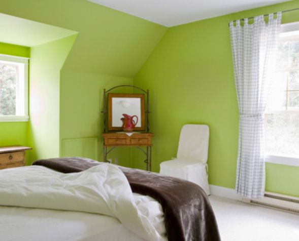 a bedroom with green walls and white bedding, along with a chair in the corner