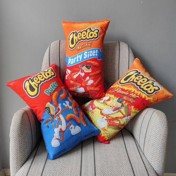 three pillows on a chair with chips in them and one pillow is orange, the other has blue