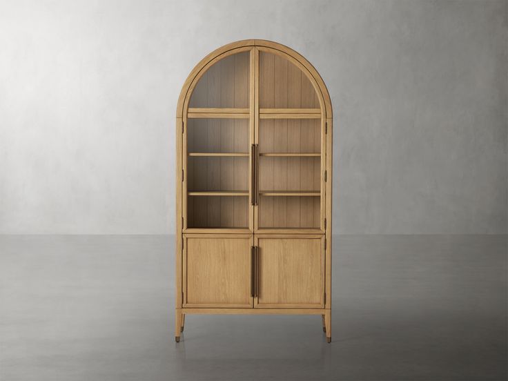 an arched wooden bookcase with glass doors