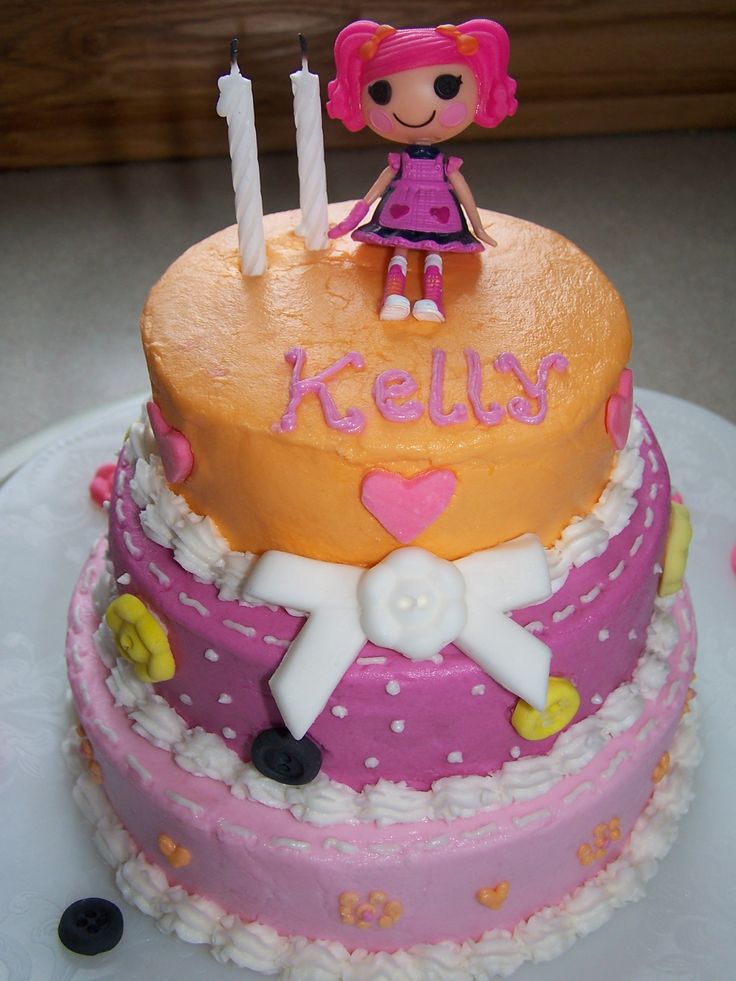 a pink and yellow cake with a doll on top