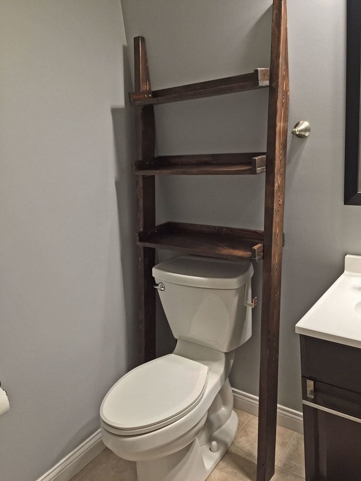 a bathroom with a ladder leaning against the wall next to a white toilet and sink