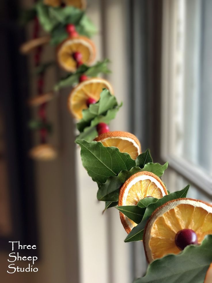 orange slices and leaves are arranged in a line on a window sill with holly